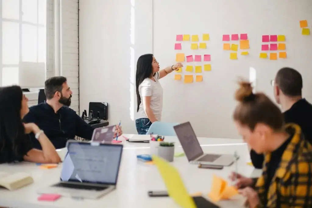 Five land professionals around a table reviewing sticky notes on a wall